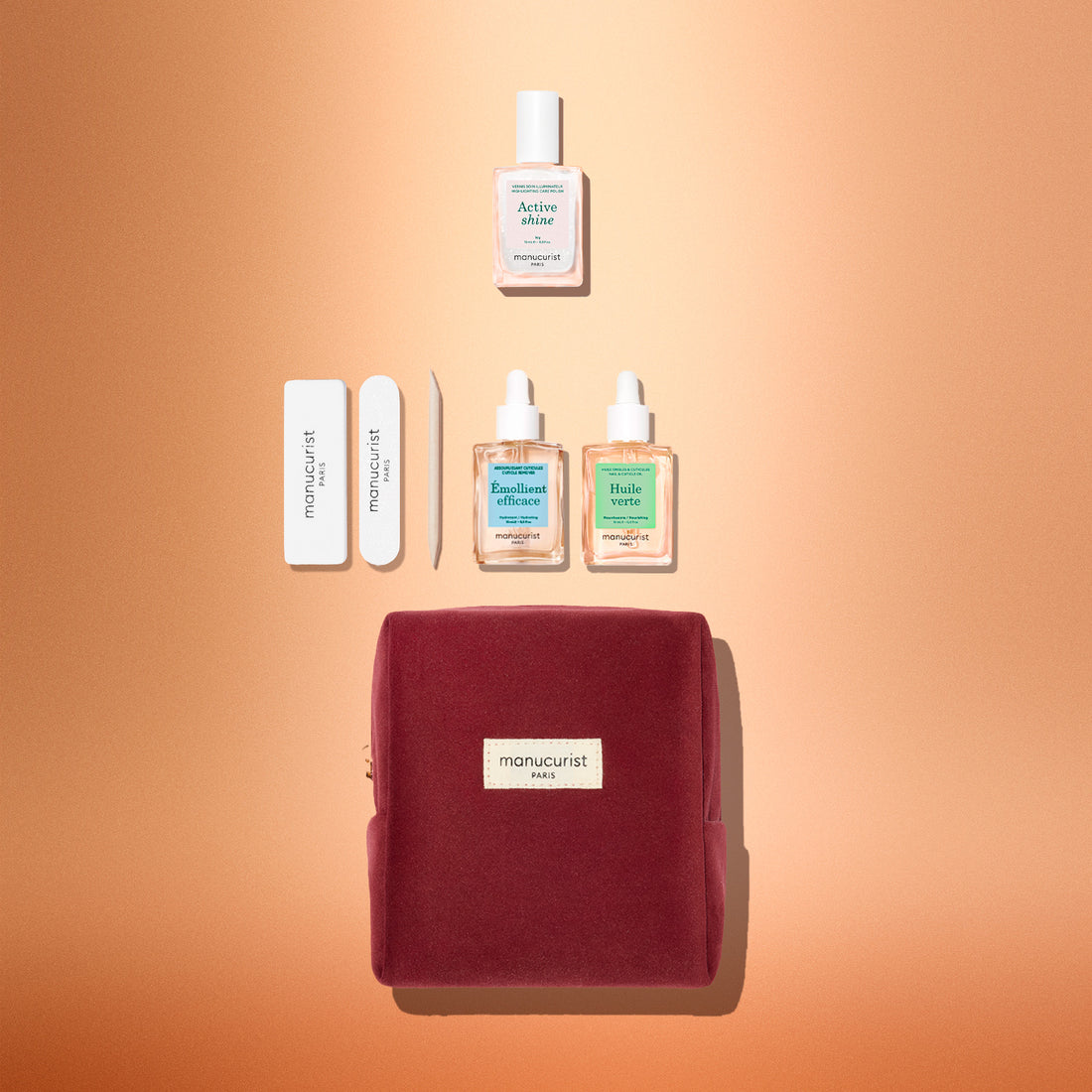 Le coffret cadeau découverte Active™ de Manucurist est joliment présenté sur un fond pêche. Il comprend une pochette en velours rouge, des limes à ongles, un repousse-cuticules, deux flacons d’huile de soin pour les ongles et un flacon de sérum pour les ongles, le tout soigneusement disposé. Un cadeau idéal pour les fêtes, à offrir à une personne qui aime prendre le temps de faire sa manucure et avoir de beaux ongles.