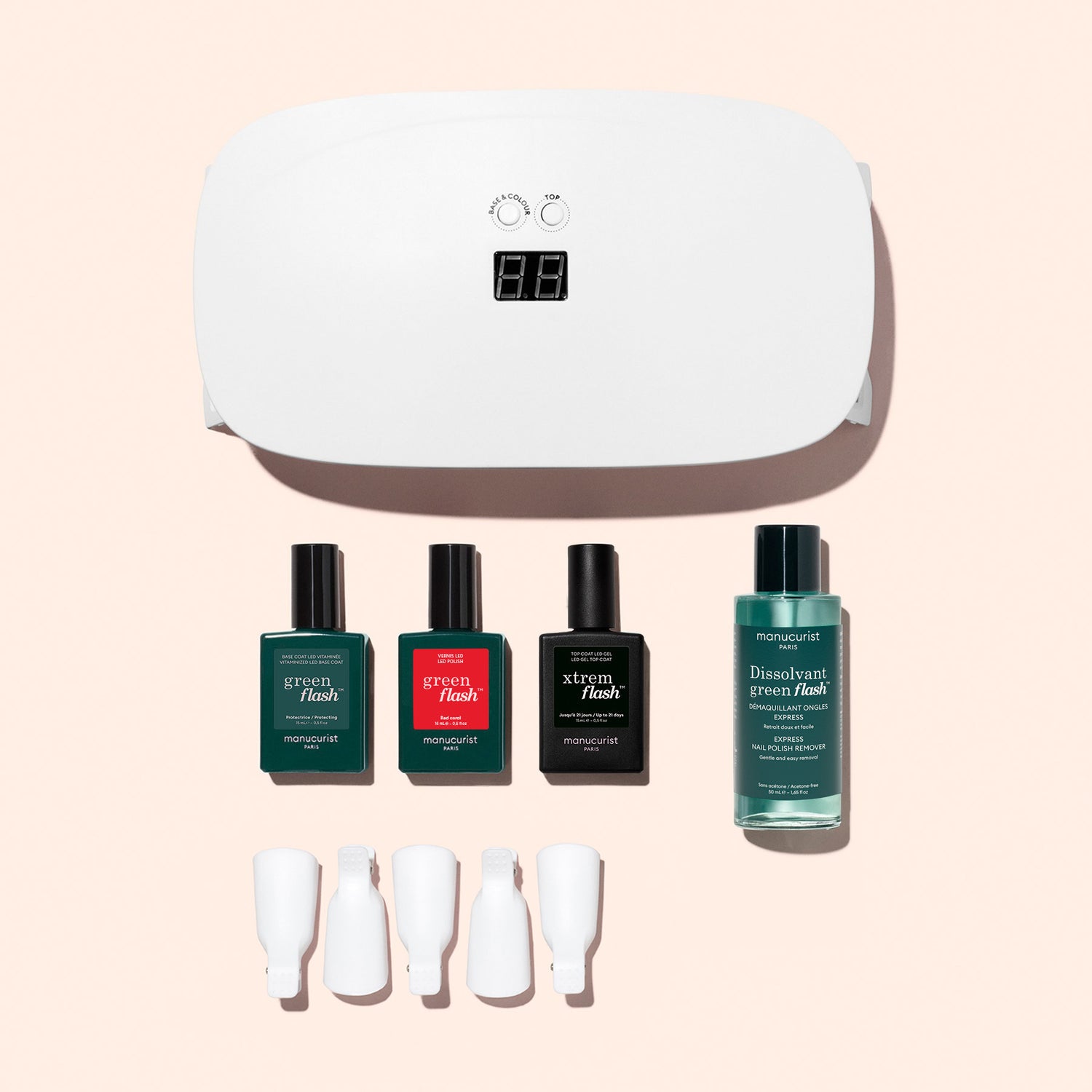 The Manucurist Discovery Kit—featuring a white UV lamp, three polishes, remover, and four clips—is displayed on a pale pink background, giving you all you need for an ultra-glossy gel manicure.