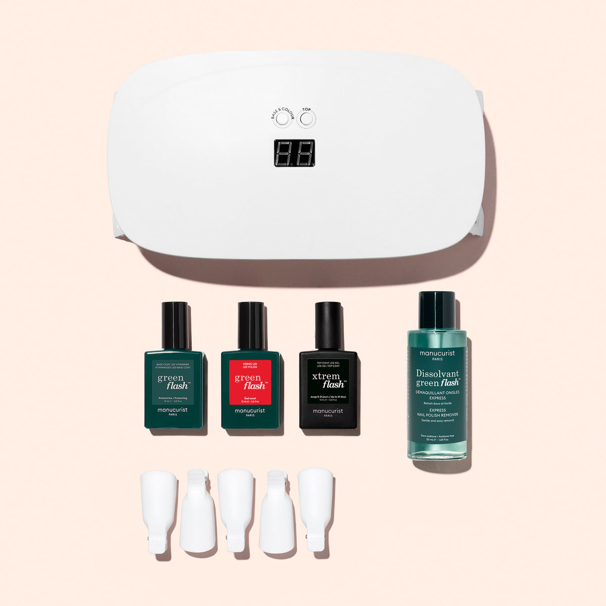 Le coffret découverte Manucurist — comprenant une lampe LED/UV blanche, trois vernis, du dissolvant et quatre pinces de retrait — est présenté sur un fond rose pâle, vous offrant tout ce dont vous avez besoin pour une manucure ultra-brillante.
