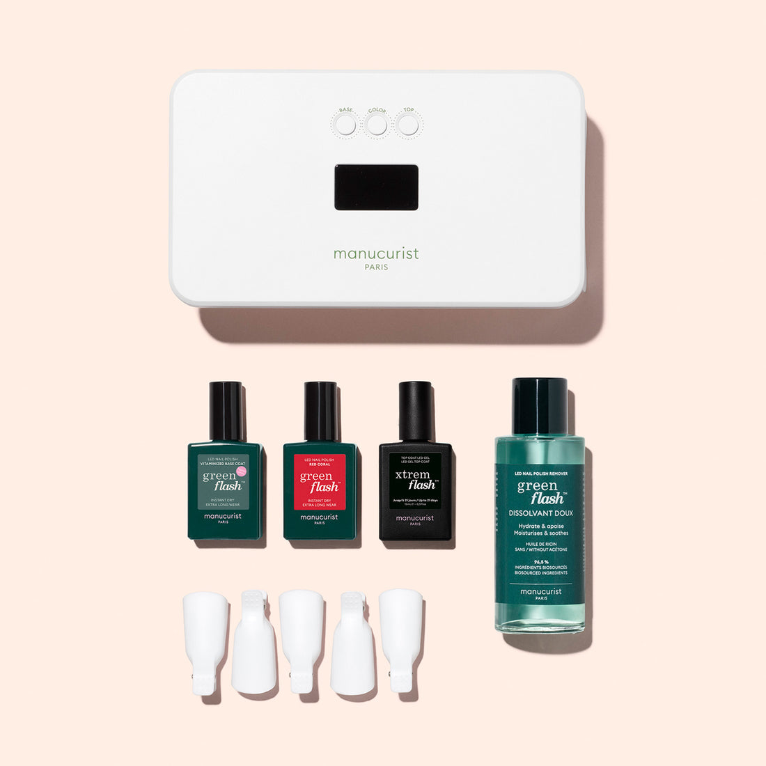 The Manucurist Discovery Kit features a white LED nail lamp, Green Flash gel polish set (three bottles), vitaminized base coat with KeraHCE+ technology, remover, and four clips—all displayed on a light peach background.