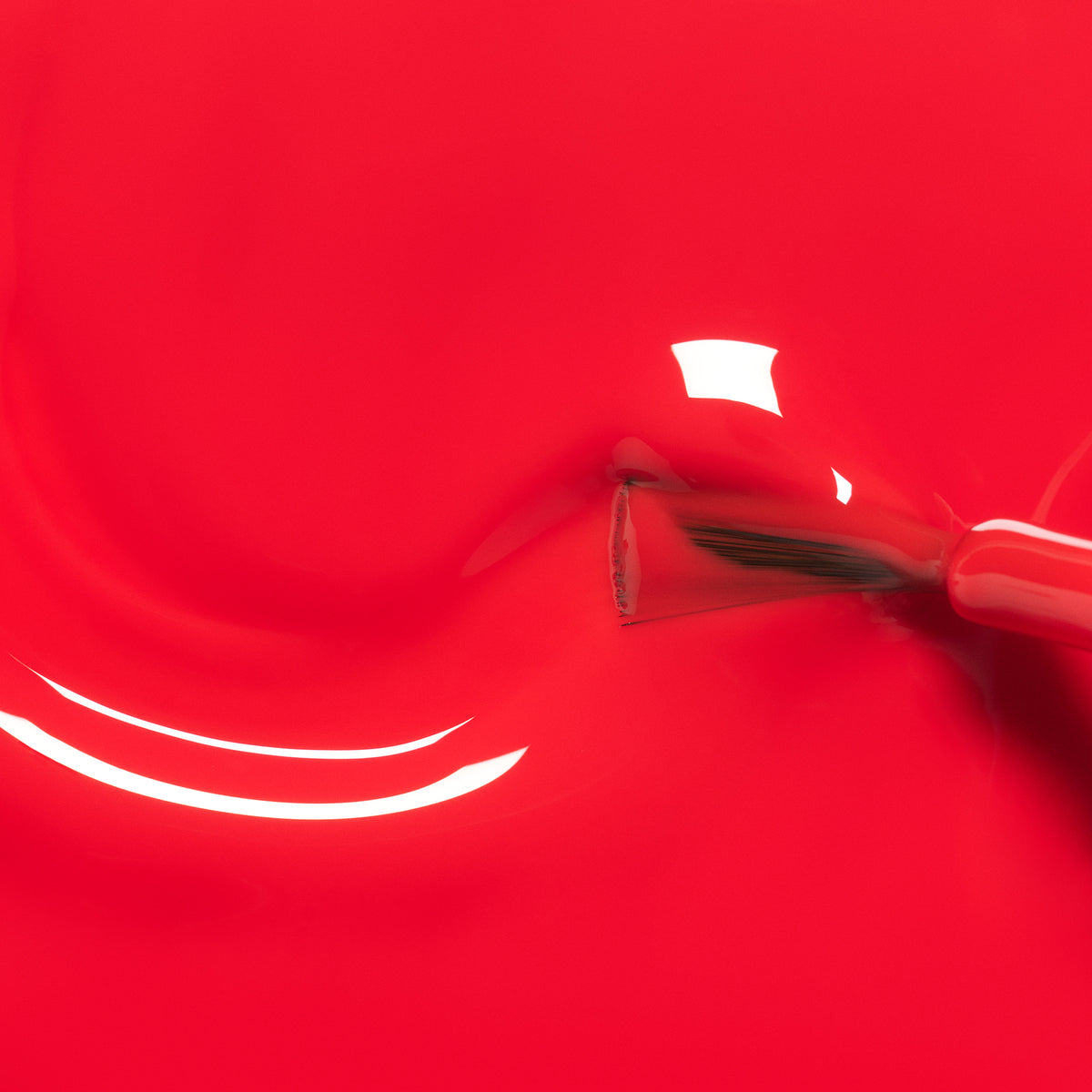 Gros plan sur le pinceau du vernis à ongles Lucette la fauvette de Manucurist appliquant un vernis rouge vif pour enfants, avec des reflets brillants sur la surface glossy — parfait pour les petites mains et formulé à partir d&