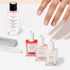 A manicured hand is displayed above bottles of nail treatments, nail polish remover, and manicure tools from the Active Manicure Kit by Manucurist, all neatly arranged on a white surface.