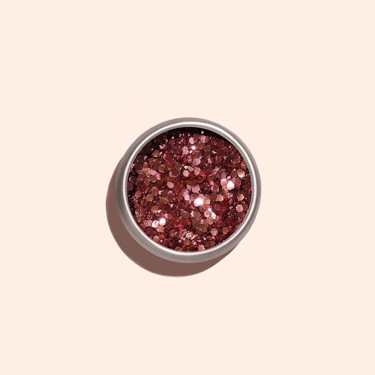 Un petit pot rond de Glitter biodégradable Pink Quartz de Manucurist, rempli de grosses paillettes rose gold brillantes, est posé sur un fond beige clair — parfait pour ajouter une touche d’éclat éco-responsable à votre Nail Art.