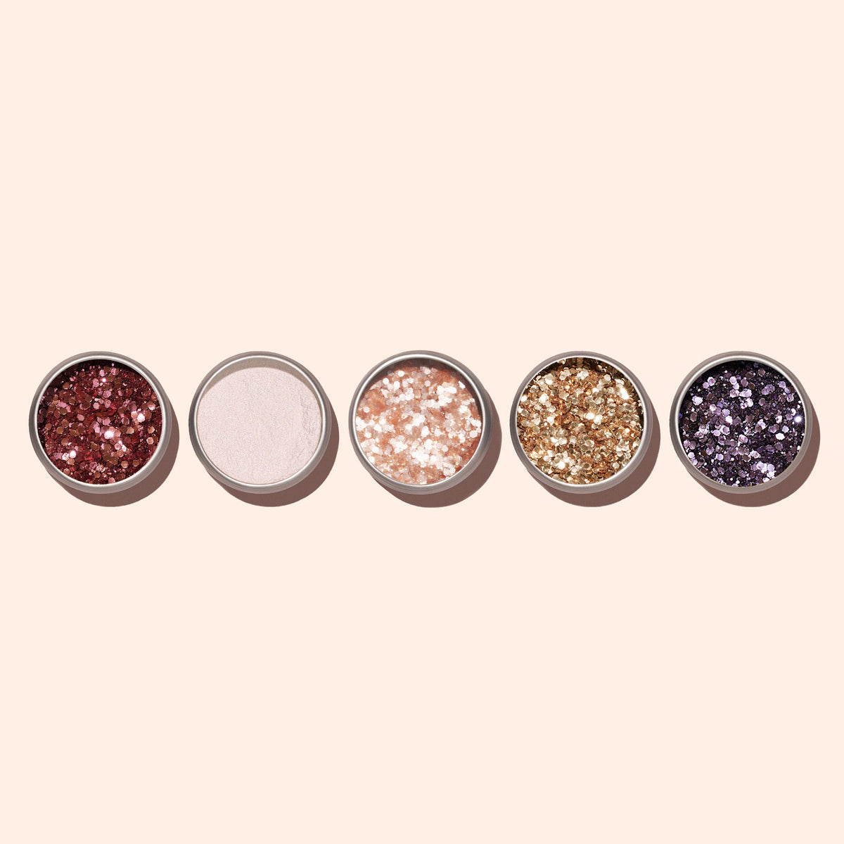 Cinq pots ronds de paillettes biodégradables Manucurist Pink Quartz en rouge, blanc, pêche, or et violet sont alignés sur un fond beige clair — idéal pour des looks glamour ou du Nail Art créatif.
