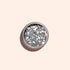 Un pot rond de paillettes biodégradables Silver Manucurist, conçu pour le nail art, repose sur un fond beige clair avec une ombre douce projetée vers la gauche.