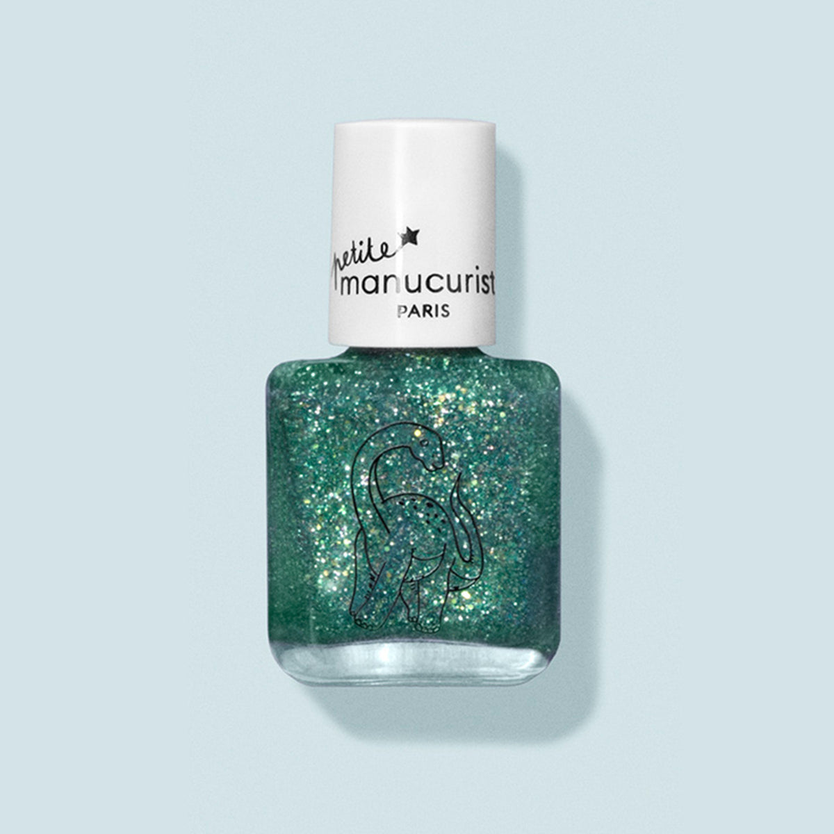 A bottle of Marius the Diplodocus kids nail polish by Manucurist, with natural ingredients, a white cap labeled petite manucurist PARIS, and a dinosaur line drawing on the bottle, set against a pale blue background.