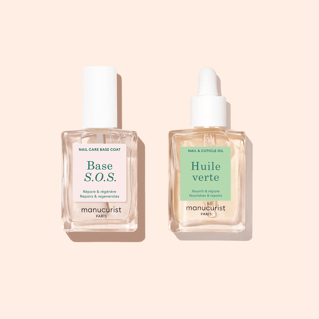Two square glass Manucurist bottles rest on a light beige background: “Base S.O.S.” with a white cap and “Nourishing Cuticle Oil” with a dropper, both designed to nourish and hydrate nails.