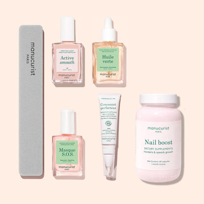 Five manicure essentials from Manucurist’s Basic Routine - Ridged Nails set—including a nail file, three bottles of nail care (such as nourishing cuticle oil), a tube of nail serum, and a pink jar of dietary supplements for healthy, ridged nails—are all arranged neatly on a light pink background.