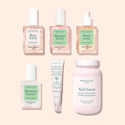 The Manucurist Ultimate Routine - Damaged Nails set, featuring six nail care products for repair—including Base S.O.S., Masque S.O.S., Huile verte cuticle oil, Kératine booster nail strengthener, Concentre perfecteur cream, and Nail boost dietary supplements—is arranged on a beige background.