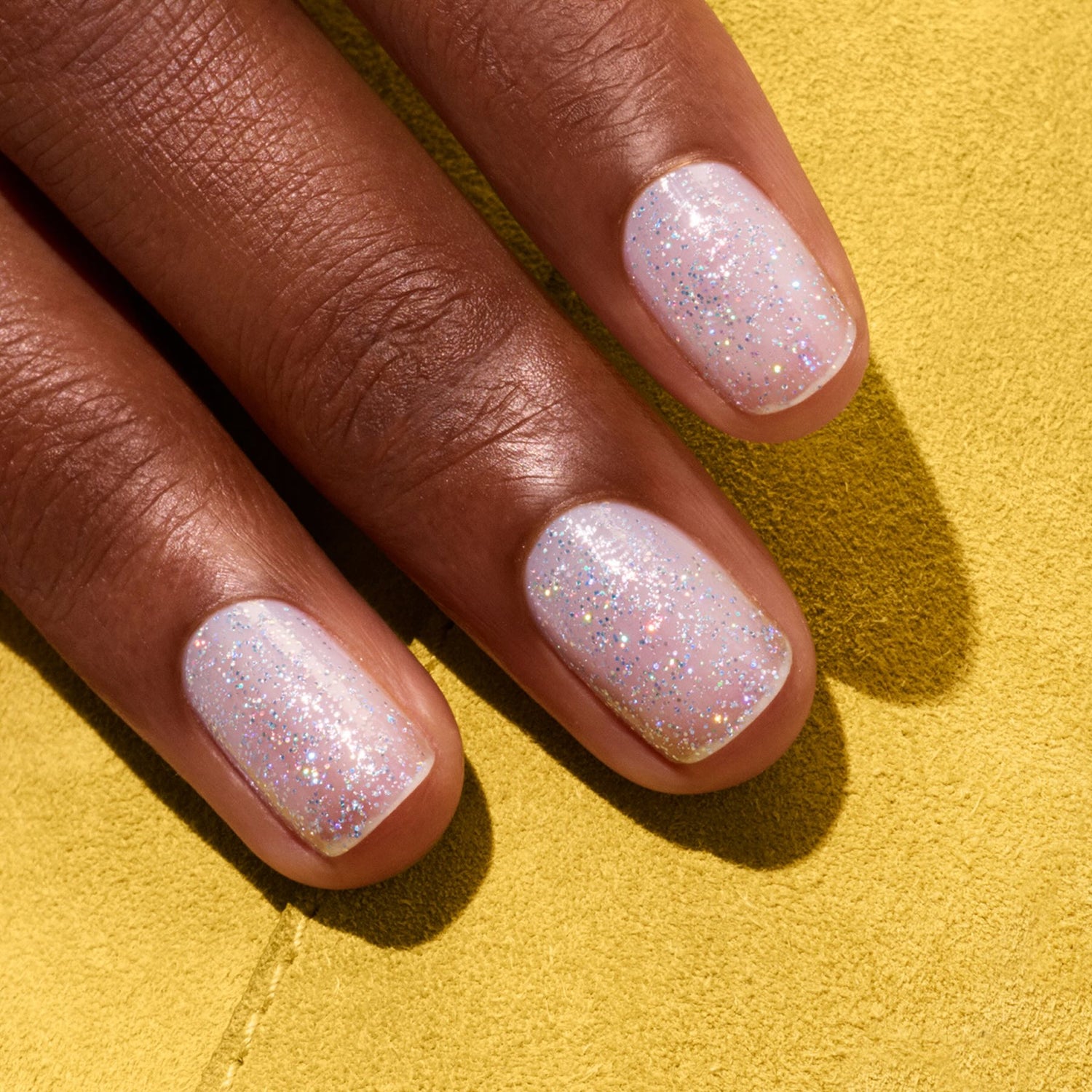 Fingers with short, neatly manicured nails painted in Manucurist&