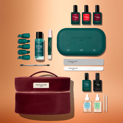 Le coffret kit de démarrage Green Flash™ de Manucurist réunit des vernis pour une manucure effet gel, un dissolvant, des limes, une lampe LED verte, des accessoires pour les cuticules, des pads de dépose et une élégante trousse bordeaux. Le tout est soigneusement disposé sur un fond orange et offre le nécessaire pour une manucure longue tenue digne d’un salon à la maison.