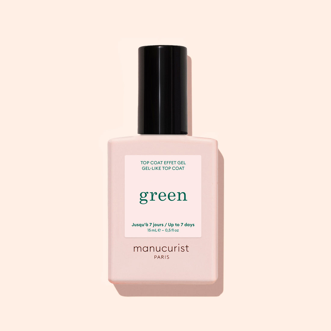 A bottle of Manucurist Green Sunshine Top Coat comes in a pale pink rectangular bottle with a black cap and white label, offering a gel-effect finish with its plant-based formula.