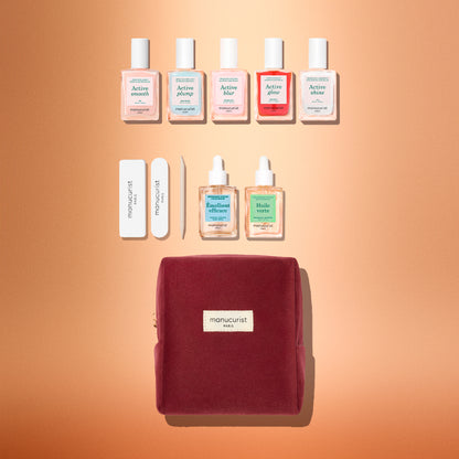 The Manucurist Active™ Super Starter Gift Set makes a perfect holiday gift, featuring six nail polish bottles, two cuticle treatments, two nail files, a cuticle pusher, and a burgundy velvet pouch—all beautifully arranged on a peach-colored background to help you achieve beautiful nails as part of your manicure routine.