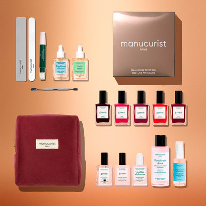 A flat lay of Manucurist’s Green™ Super Starter Kit Gift Set, featuring naturally derived nail polishes, remover bottles, nail files, a cuticle pusher, two serum bottles, and a red fabric pouch—all beautifully arranged on a light brown background.
