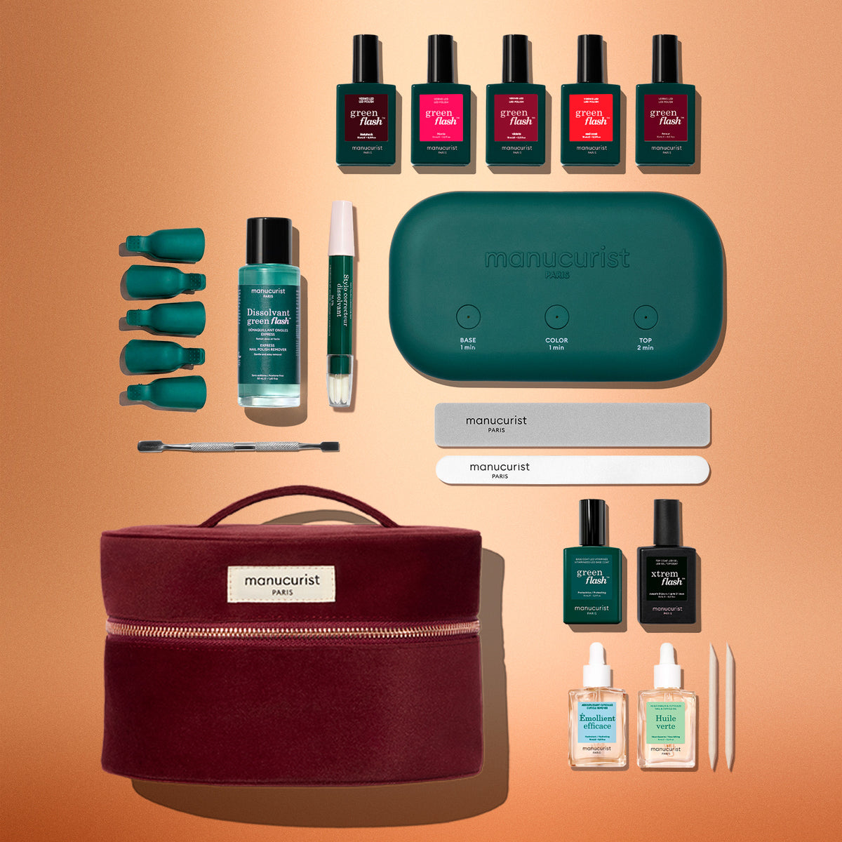 The Manucurist Green Flash™ Super Starter Kit Gift Set includes nail polishes, remover clips, nail tools, a green LED lamp, files, and comes in a chic burgundy case—all artfully arranged on a peach background—making it perfect for achieving salon-quality manicures or long-lasting nails at home.