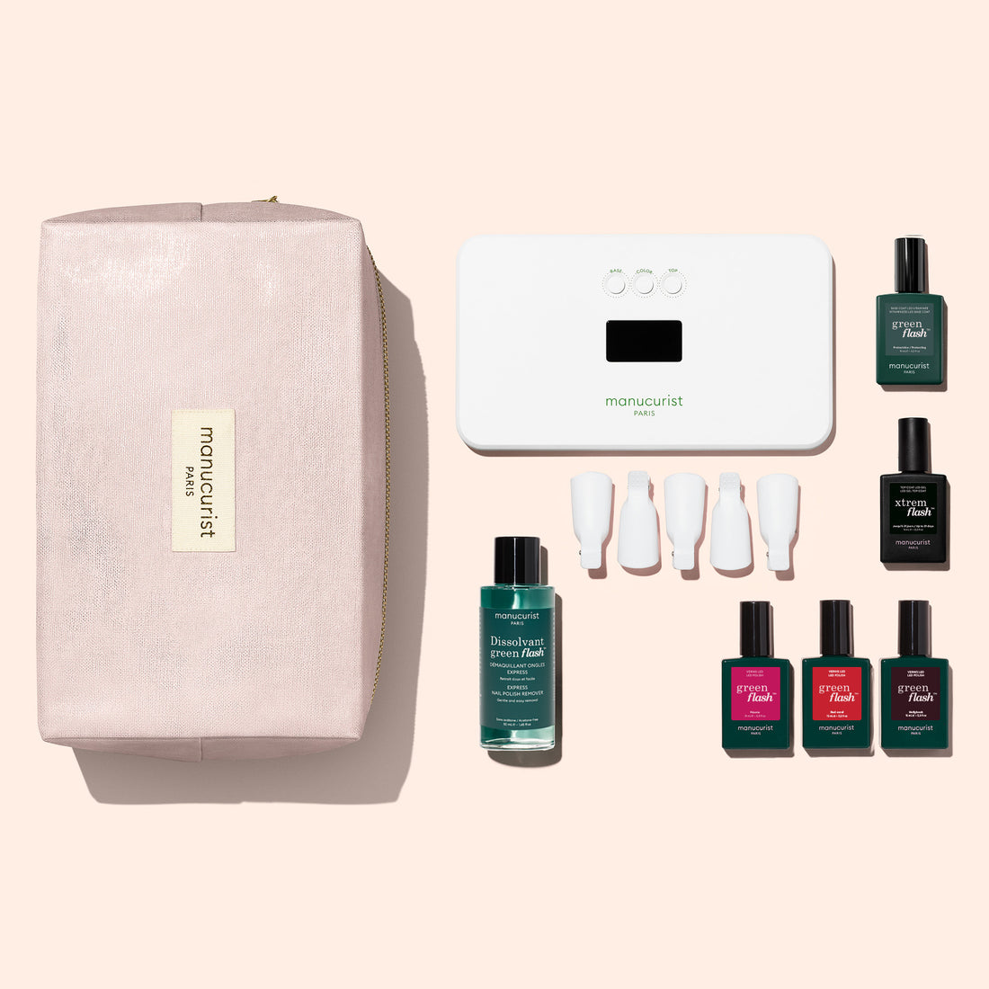 The Manucurist Starter Kit, featuring a pink Manucurist pouch, a sleek white LED nail lamp, green nail polish remover, four vibrant shades of nail polish, three white nail caps, and a dark green bottle—all arranged neatly on a light pink background—contains everything you need for an ultra-glossy manicure or to complete your gel polish kit.