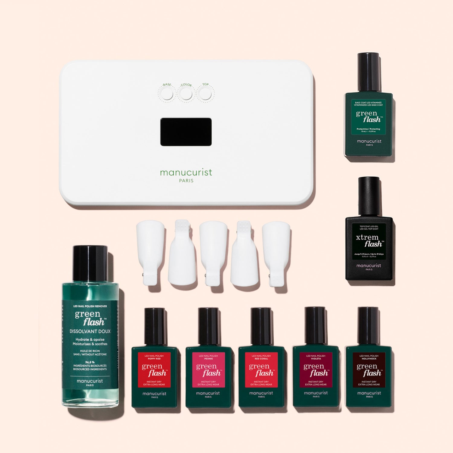 The Manucurist Super Starter Kit includes a UV lamp, six green flash gel polishes, remover, four white nail clips, and two black bottles—all displayed on a light pink surface for an ultra-glossy manicure.