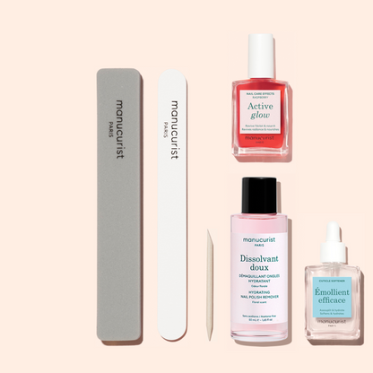 The Manucurist Active Discovery Kit includes four essential manicure products and two nail files, all arranged neatly on a light peach background—featuring nail polish, remover, hydrating treatment drops for nails and cuticles, and a wooden cuticle stick. This curated set is everything you need for a flawless manicure and an elevated nail care routine.