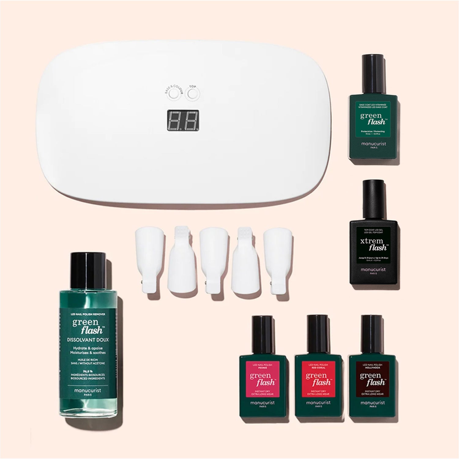 The Manucurist Starter Kit includes a UV lamp, four green polishes, a vitaminized base coat, remover, and white nail clips—perfect for an ultra-glossy manicure, all arranged on a light pink background.