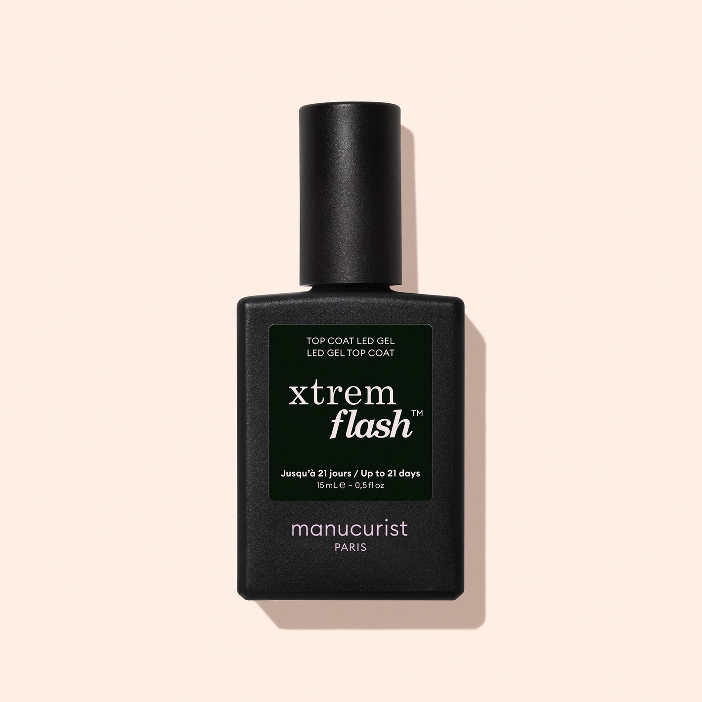 A black bottle of Manucurist-test [Influence] Top Coat Xtrem Flash is pictured upright on a light pink background, featuring a dark green label with white text.