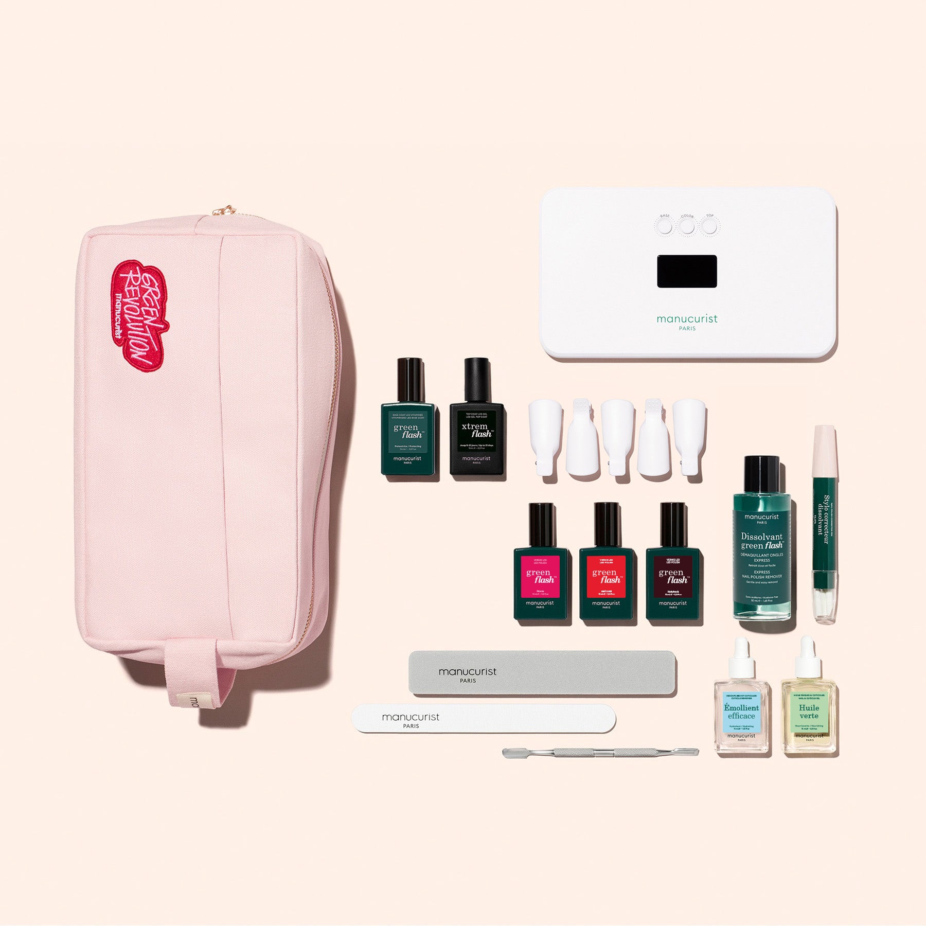 The Manucurist Ultimate Kit, featuring a pink toiletry bag, gel polish bottles, nail file, buffer, cuticle pusher, and white LED lamp, is arranged on a pale background—perfect for achieving an ultra-glossy manicure at home.