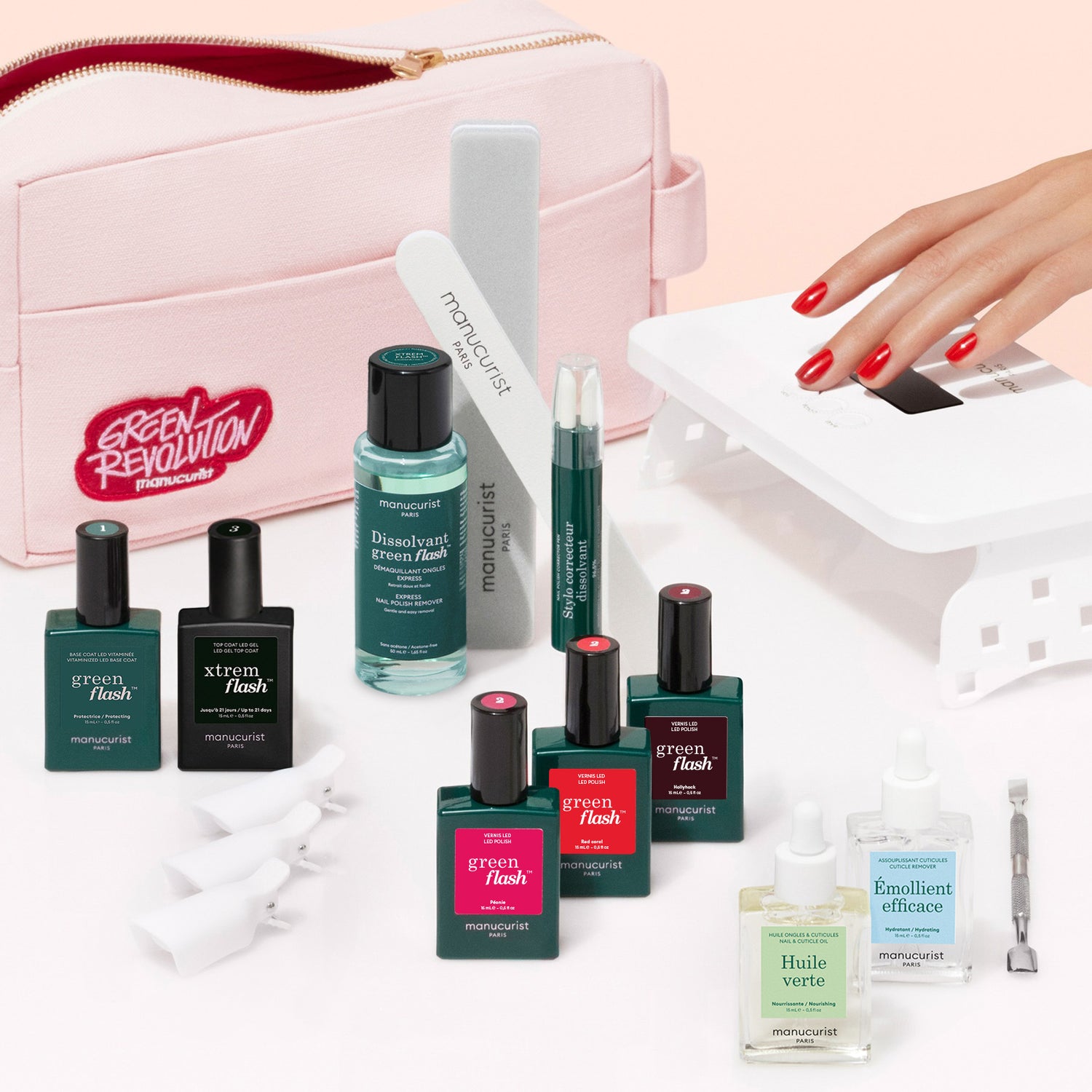 The Manucurist Ultimate Kit includes gel polish, nail files, remover, cuticle oil, a pink bag, and a UV lamp for ultra-glossy red nails. Various tools and a vitaminized base coat are displayed on a white surface.