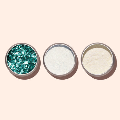 Three round metal containers on a beige background, filled from left to right with Manucurist Turquoise Biodegradable Glitter for nail art, white powder, and off-white powder.