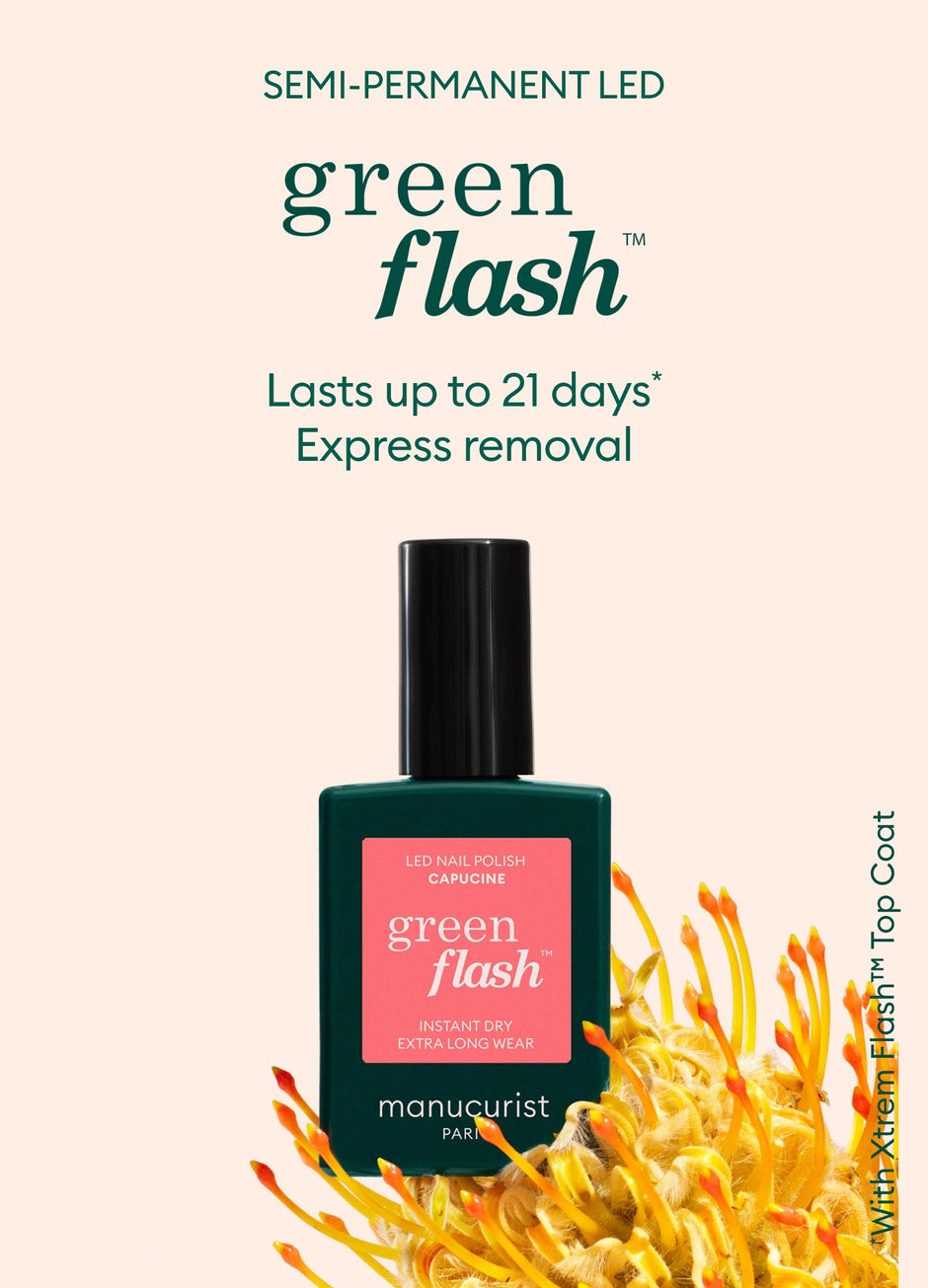 A bottle of Manucurist Green Flash LED nail polish stands upright against a pale background with yellow flowers at the bottom. Text above describes it as semi-permanent, lasting up to 21 days, with express removal.