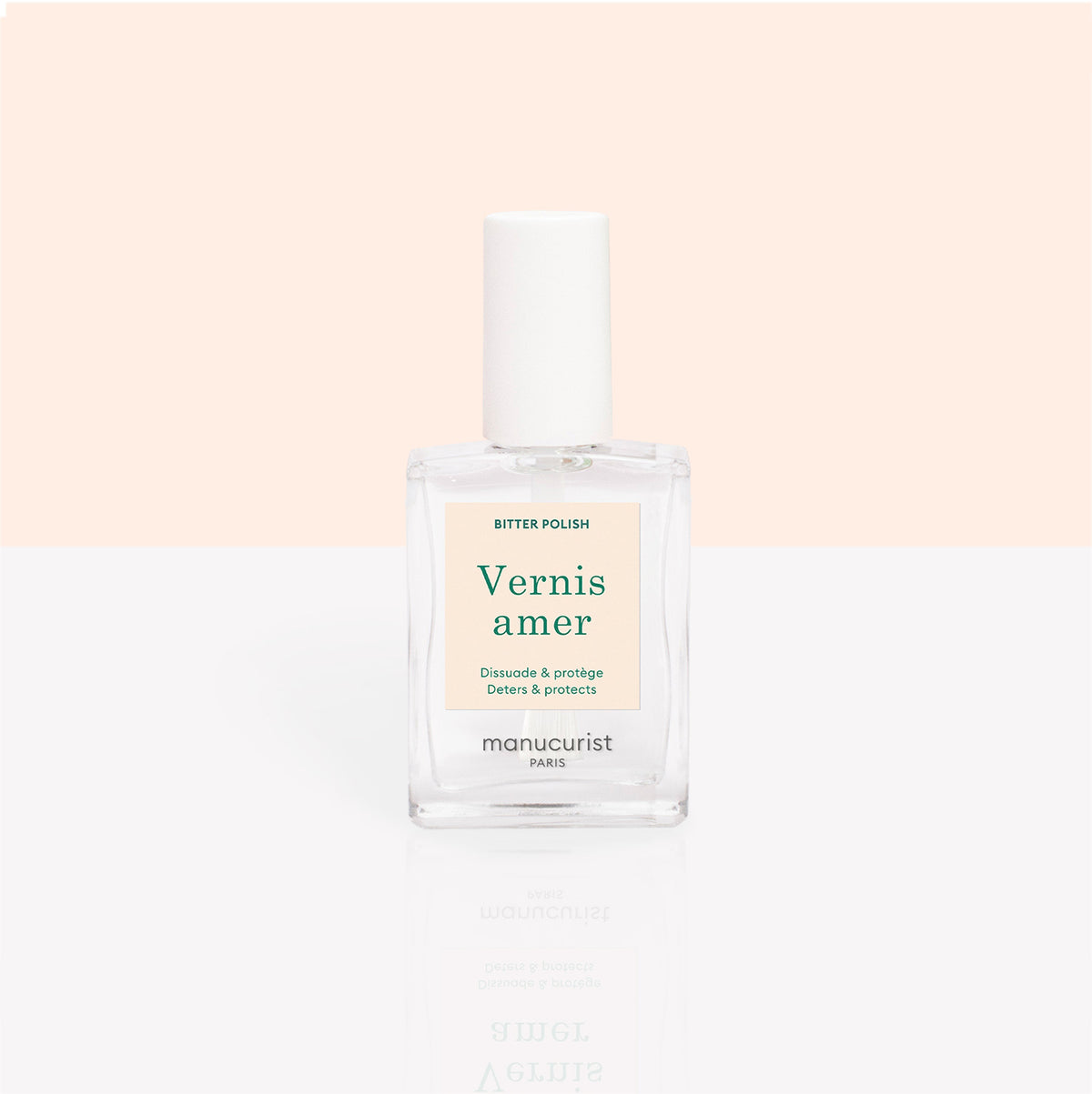 Un flacon transparent de Vernis amer Manucurist, pour le soin des ongles et pour décourager de les ronger, est présenté sur un fond pêche et blanc doux. L&