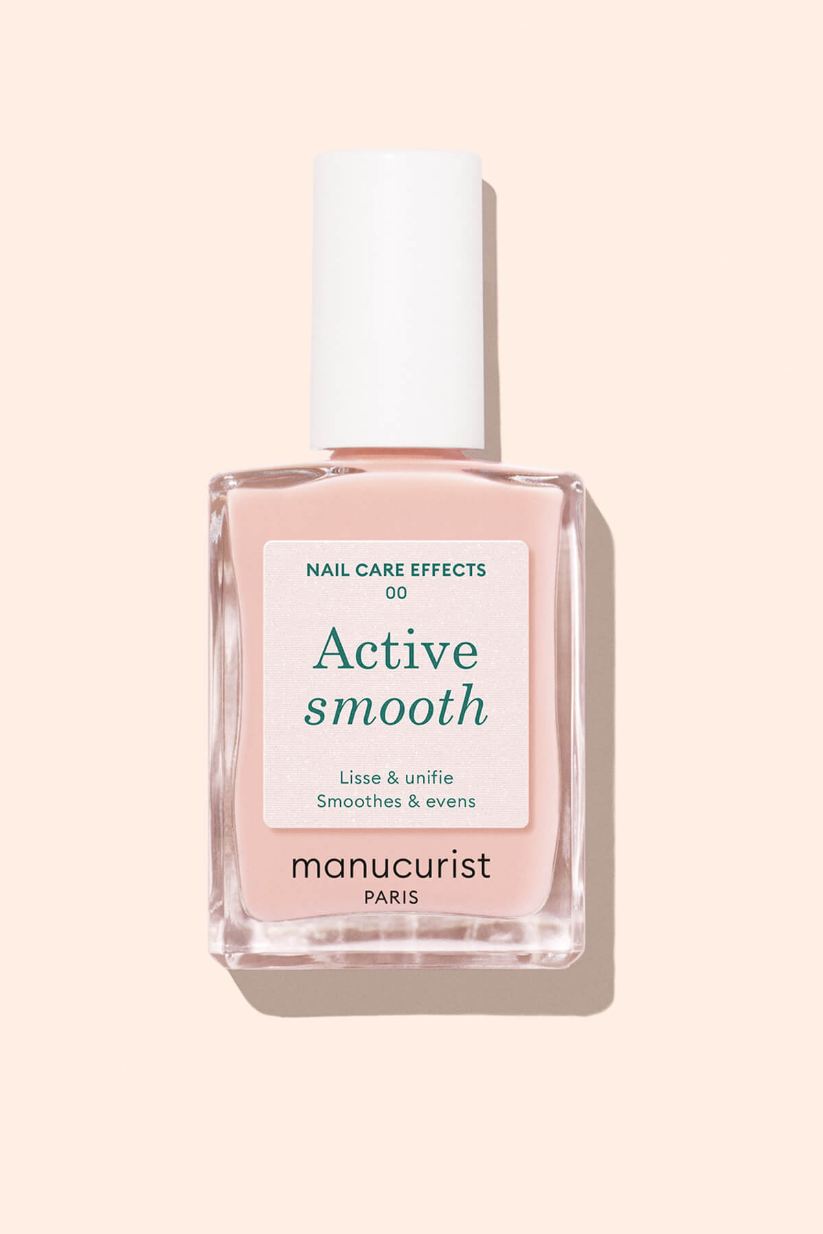 A bottle of Manucurist Active Smooth nail care polish with a white cap, pale pink liquid, and a label that reads Active smooth and Smoothes  evens on a light beige background.
