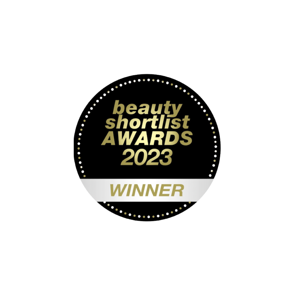 Un badge circulaire noir avec un texte doré indiquant beauty shortlist AWARDS 2023 et un ruban blanc en bas avec WINNER en doré, entouré d’une bordure pointillée.