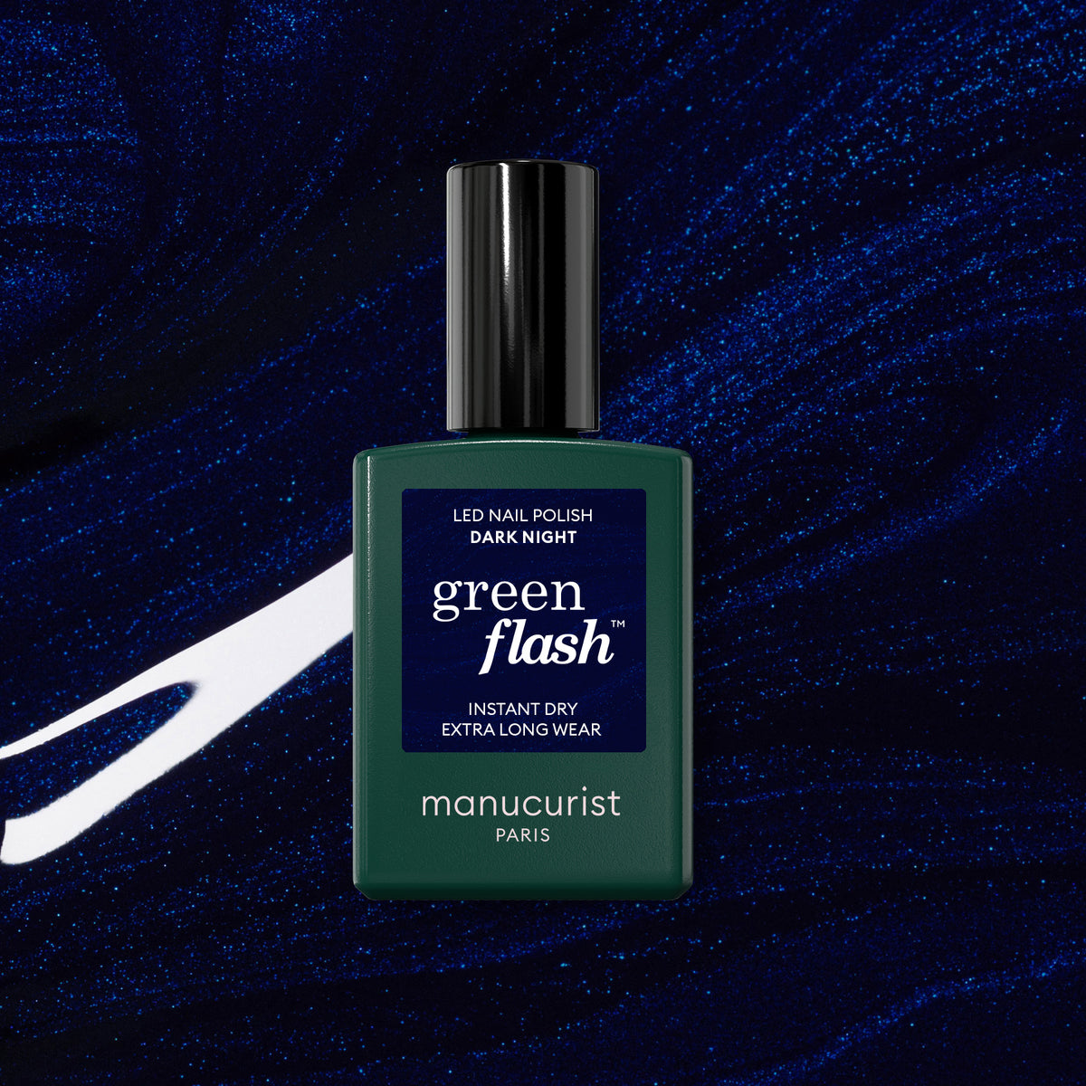 Un flacon de vernis gel Manucurist Dark Night est présenté sur un fond abstrait bleu foncé et scintillant avec des traînées blanches.