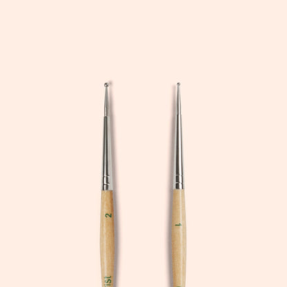 Two Manucurist Dotting Tools with metal tips and FSC wood handles are shown standing upright side by side on a light beige background, ideal for creating precise nail art designs.
