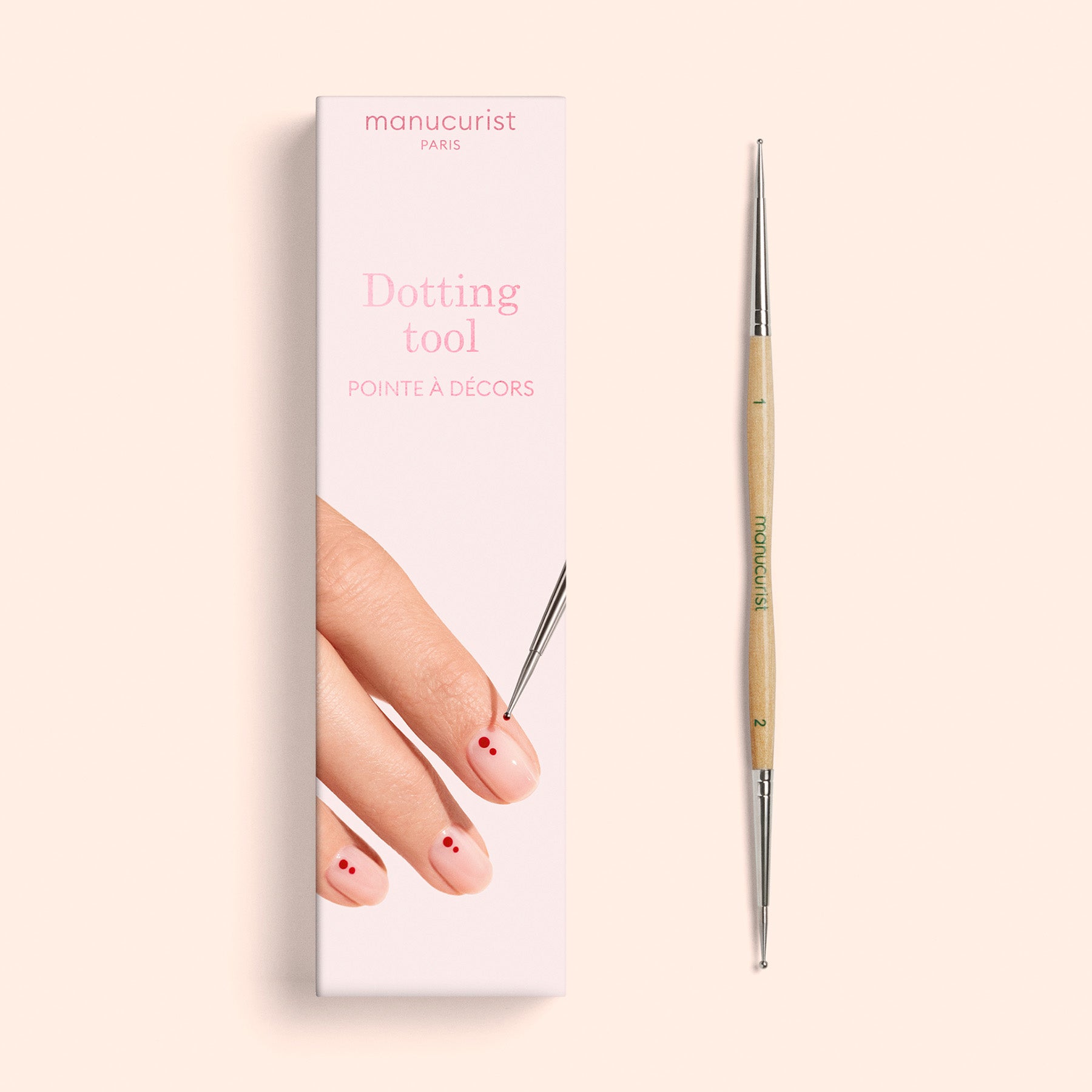 The Manucurist Dotting Tool is pictured alongside its box, which features an illustration of a hand with red dots on the nails being artfully decorated—demonstrating this professional-quality tool’s suitability for creating precise nail art designs.