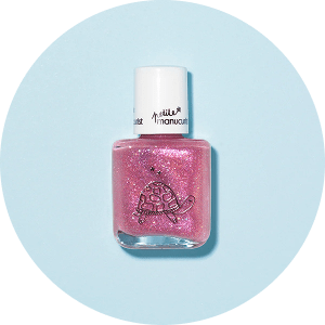Un flacon de vernis à ongles rose pailleté avec une illustration de tortue sur le devant, placé sur un fond bleu clair.