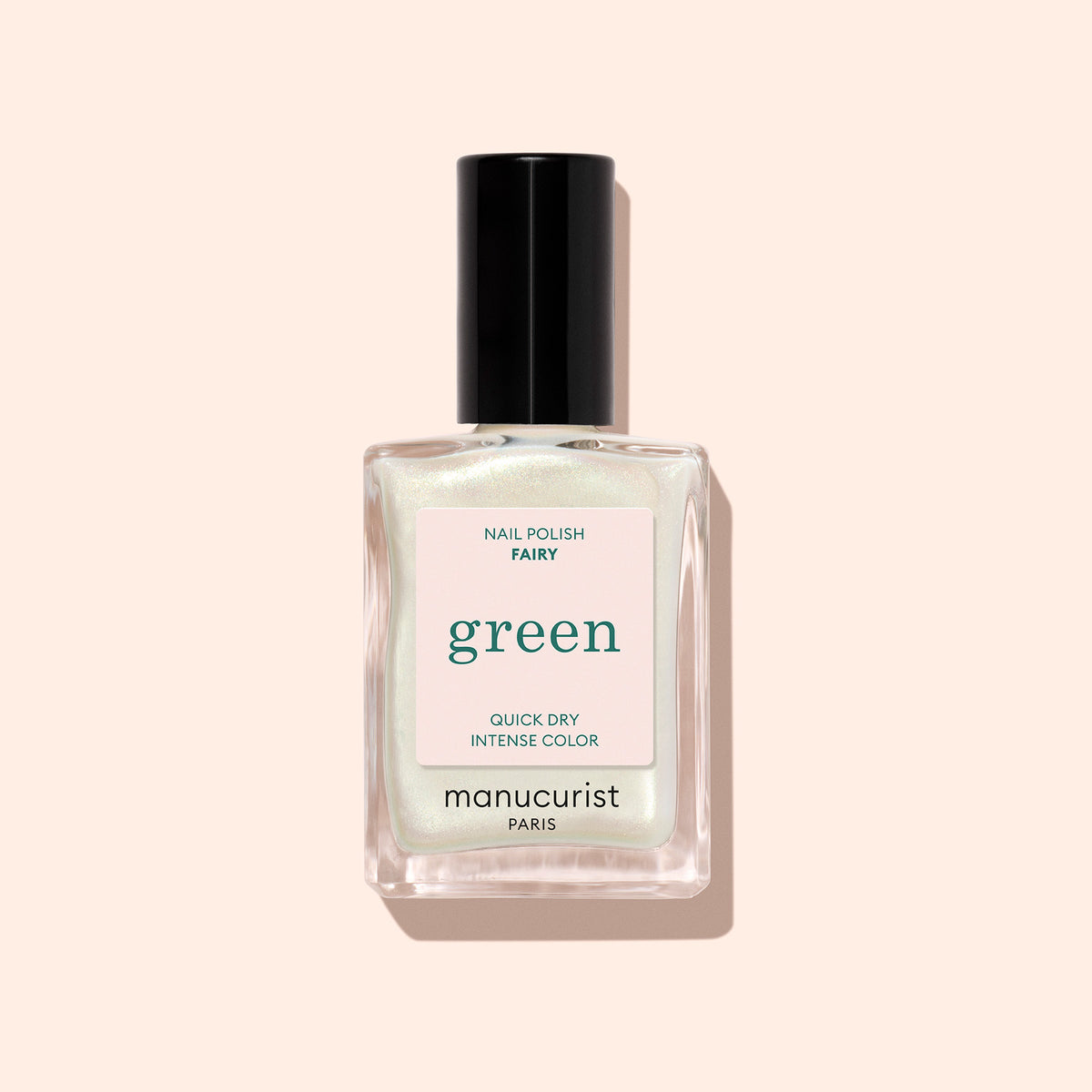 Un flacon en verre transparent de vernis à ongles Manucurist Fairy avec un bouchon noir, orné de paillettes vertes et portant les mentions QUICK DRY et INTENSE COLOR, sur un fond pêche clair.