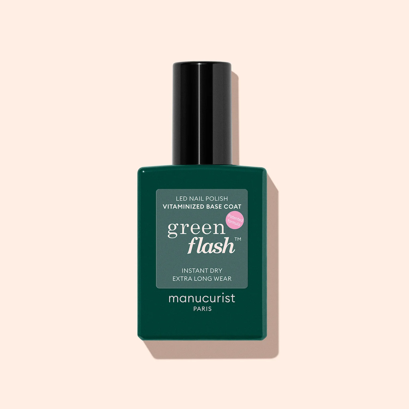 A dark green bottle of Manucurist Vitaminized Base Coat Green Flash™ with a black cap is shown on a light beige background.