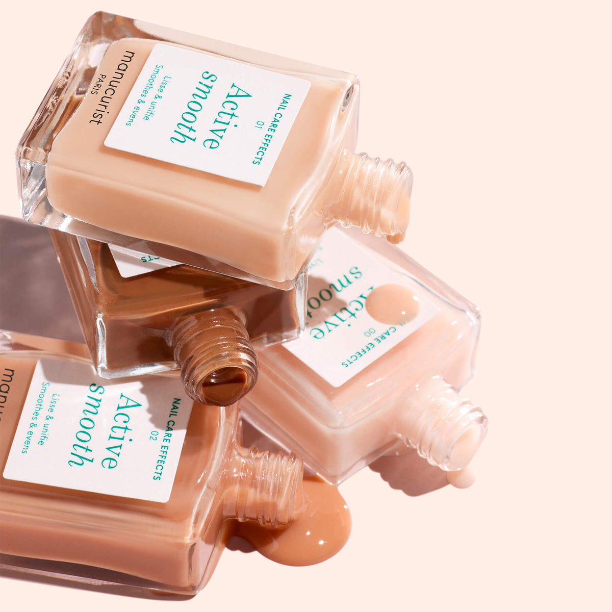 Trois flacons du pack personnalisable de 5 soins Active Manucurist sont empilés et inclinés, avec des teintes beige, havane clair et marron moyen coulant sur une surface rose pâle pour de superbes effets sur les ongles et un look personnalisé.
