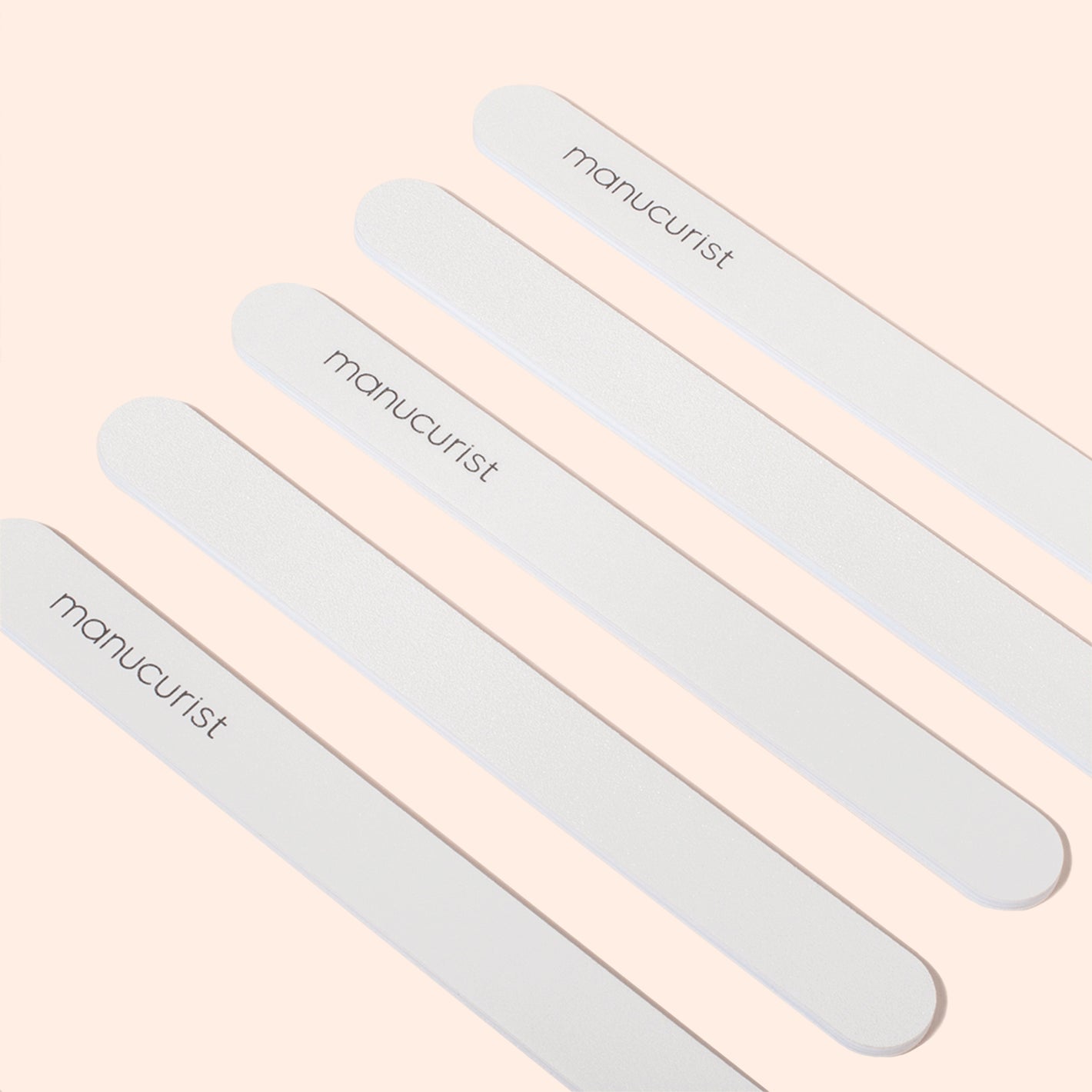 Five Manucurist Emery boards are arranged diagonally on a light beige background. Each file, featuring a fine grit surface, displays the brand name Manucurist printed in black letters.