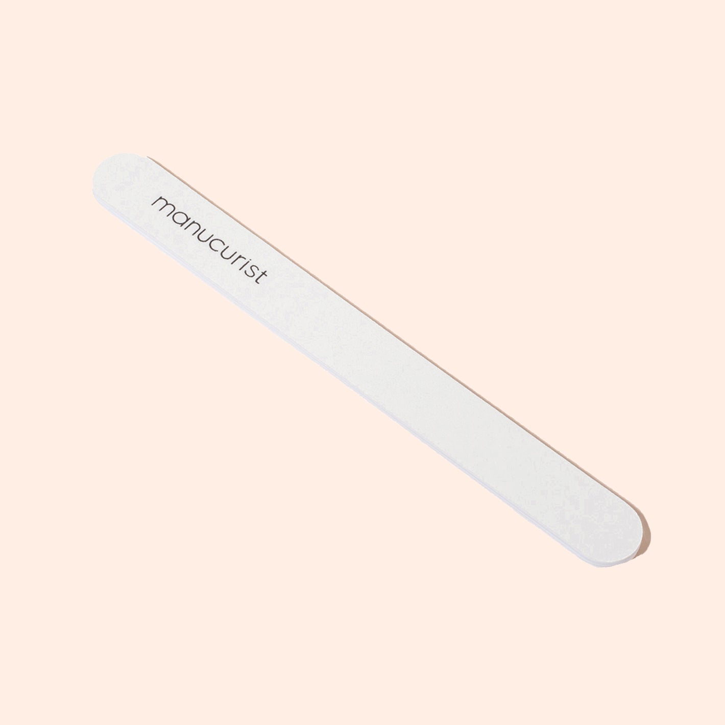 The Manucurist-us 1 Nail File, a white 100/180 grit emery board with rounded edges and "manucurist" printed on it, is ideal for shaping natural nails and is shown on a light beige background.
