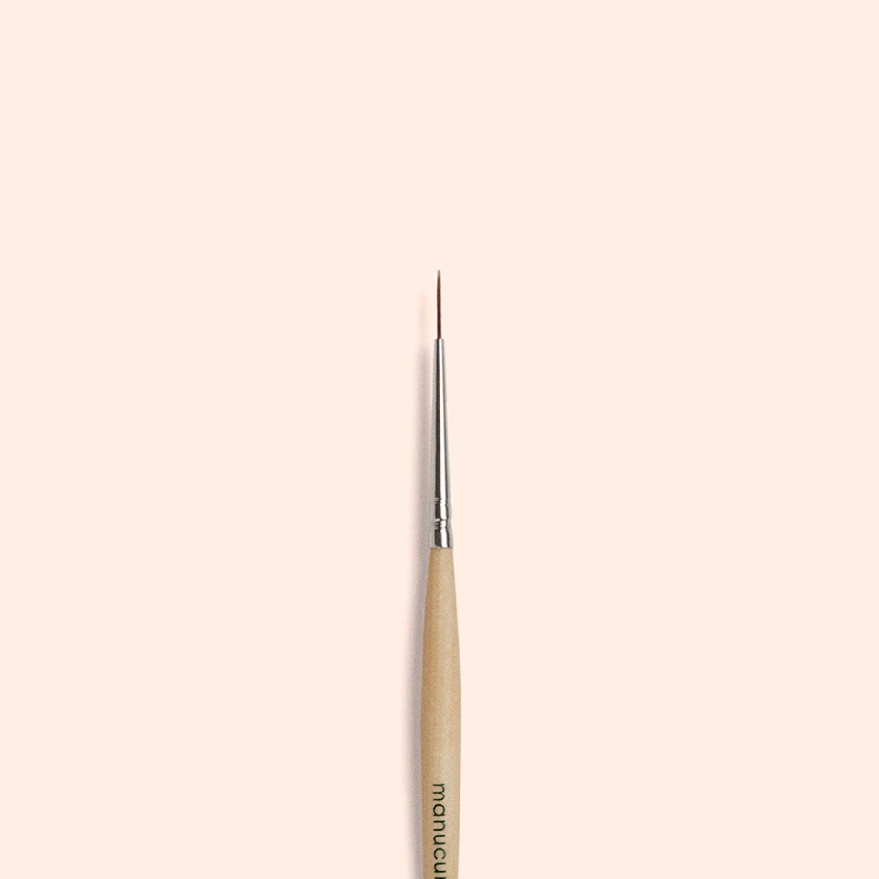 The Manucurist Liner Brush, featuring vegan synthetic bristles and a fine tip, is vertically centered on a simple light beige background.