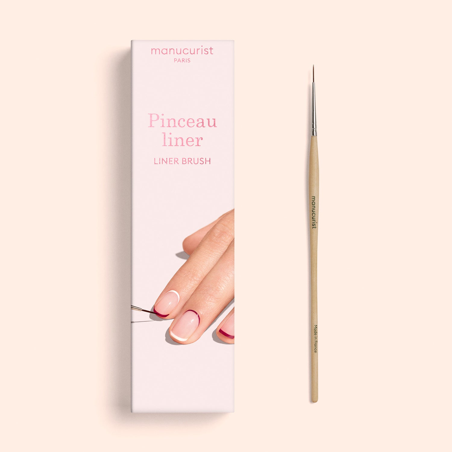 A box labeled “Liner Brush” by Manucurist, featuring an image of manicured nails and a thin nail art brush applying polish, displayed beside the actual fine-tipped liner brush made with professional quality vegan synthetic bristles.