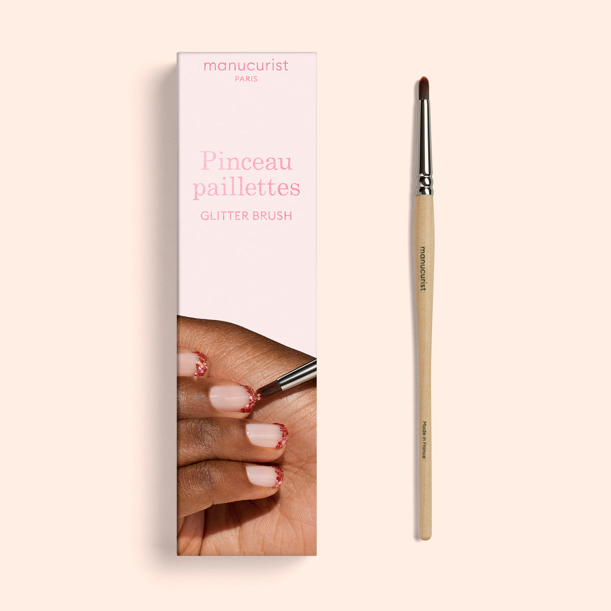 A Glitter Brush by Manucurist sits beside its box, which displays a hand with red glitter on the fingernails. The packaging is labeled “Manucurist Paris Pinceau paillettes GLITTER BRUSH” and highlights vegan synthetic bristles—ideal for giving your manicure a sparkling finish.