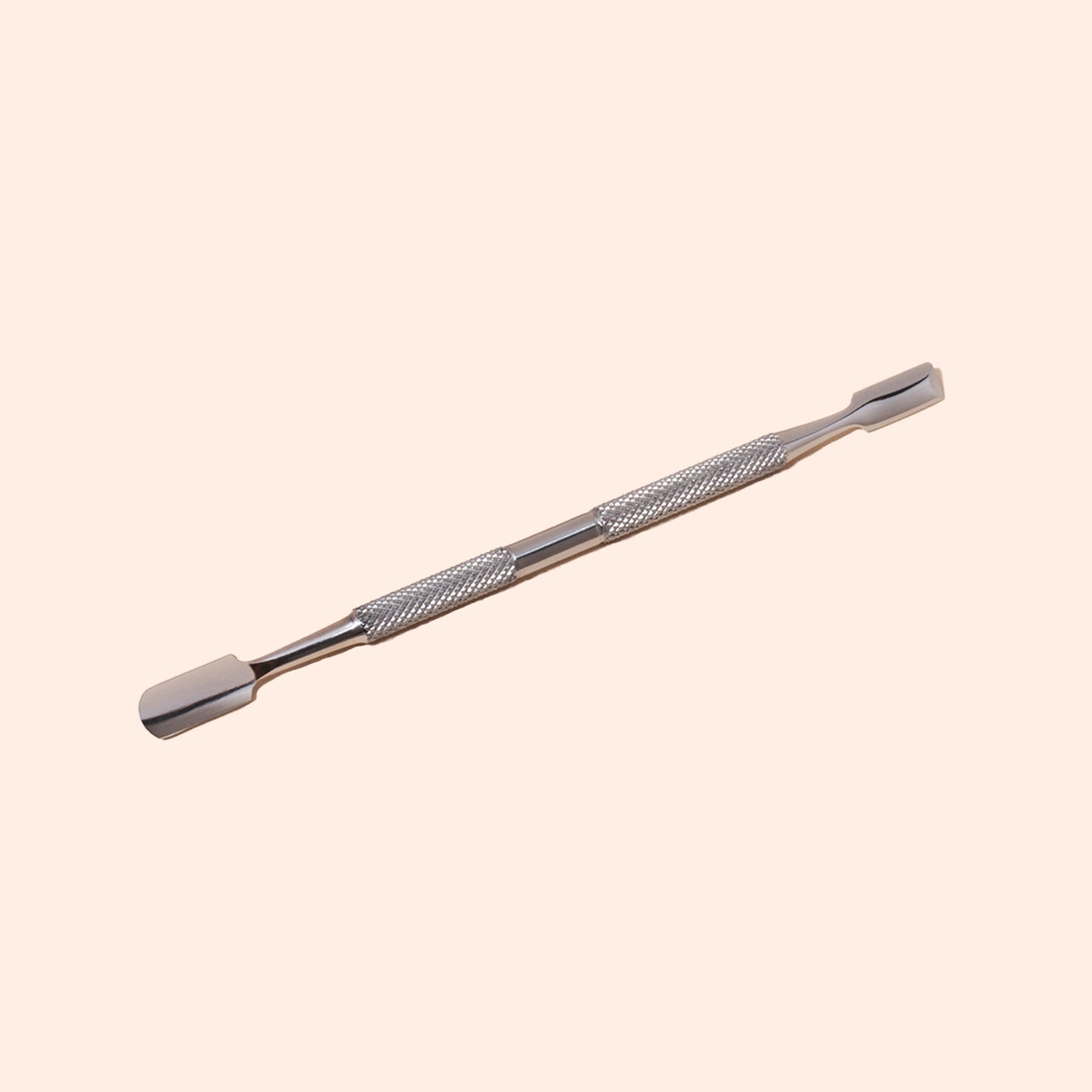 The Manucurist Cuticle Pusher, made of stainless steel with a textured grip and dual flat, rounded tips, is shown on a light beige background—an essential tool for precise nail care.