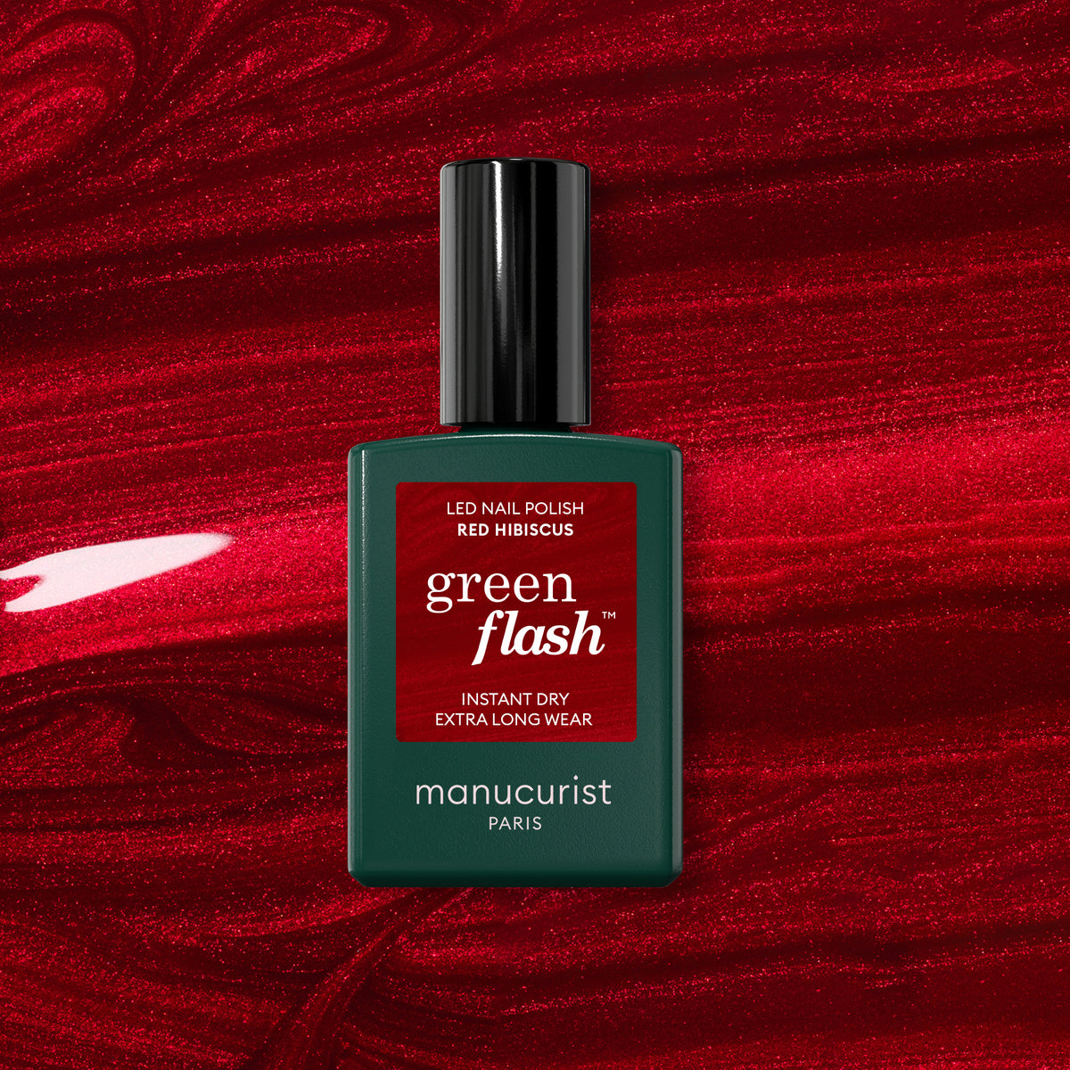 Un flacon de vernis gel Manucurist Red Hibiscus repose sur un fond rouge vif et brillant.