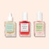 Three square glass bottles of Manucurist nail care products are lined up: a serum with a dropper, an Active Glow treatment, and a pink Masque S.O.S. nail mask, all with labels facing forward on a beige background.