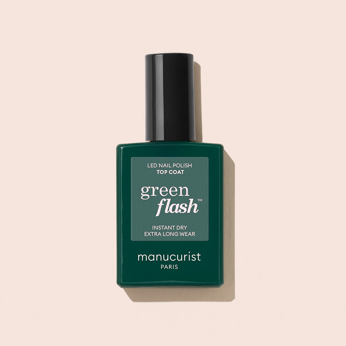 A bottle of Manucurist Green Flash™ Base Top Remover Trio with a rectangular green label and black cap is pictured against a light beige background.