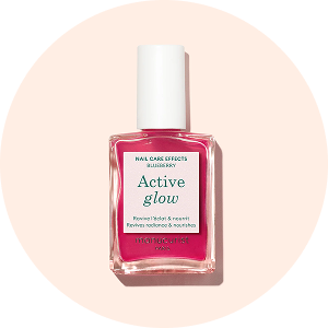 Un flacon de vernis à ongles rose étiqueté Active Glow avec un capuchon blanc, posé sur un fond circulaire pêche clair. L'étiquette mentionne les effets de soin des ongles, myrtille, fleur, hibisk et muesli.
