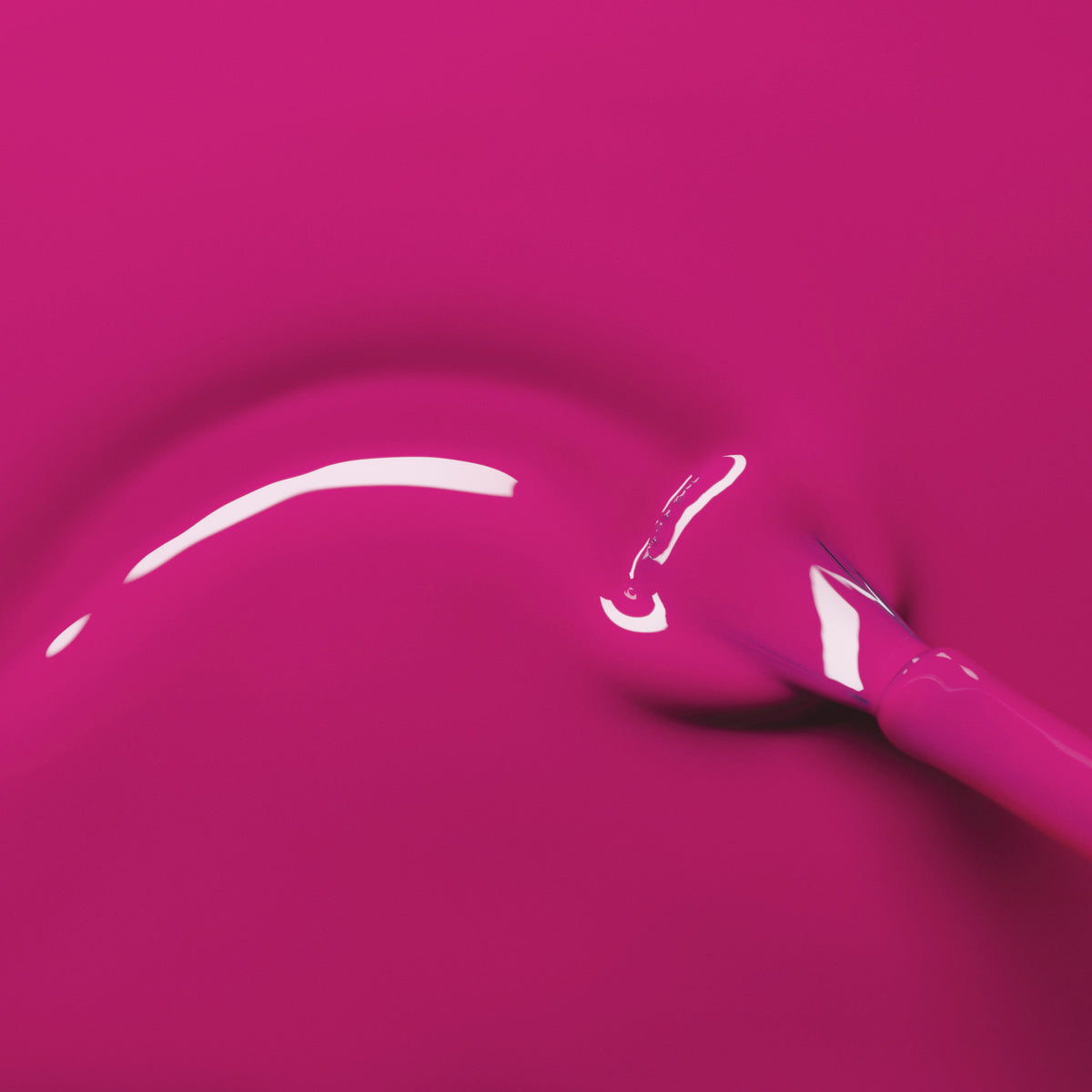 A Manucurist brush glides Armeria’s glossy, bright pink gel polish in a smooth curve across a matching pink background, revealing a shiny, reflective finish.