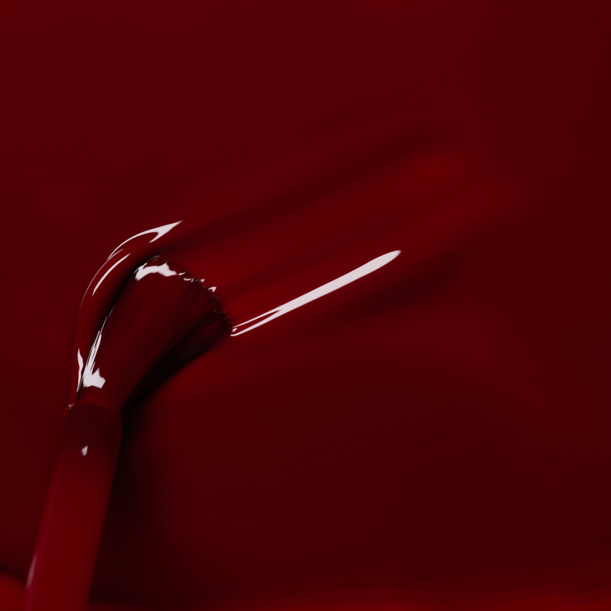 Gros plan sur un pinceau appliquant le vernis à ongles Dark Pansy de Manucurist, révélant des traits rouges lisses et brillants sur un fond cramoisi profond.
